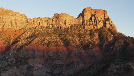 Drone-aerial-view-of-Springdale-Zion-National-Park-rock-sandstone-formations-illuminated-by-sunset-sunlight