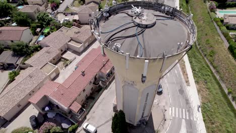 Water-tower-in-Gignac-France,-with-cellular-equipment-and-cables,-Aerial-orbit-around-high-shot