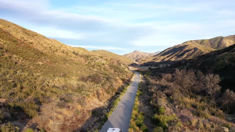 Excellent-Aerial-Of-A-Van-Driving-Between-Small-Mountains-In-Ojai,-California