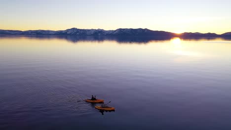 Drone-Aerial-At-Sunset-Of-Two-Kayaks-Kayakers-Couple-Kayaking-Rowing-On-The-Calm-Waters-Lake-Tahoe,-Nevada,-California