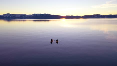 Drone-Aerial-At-Sunset-Of-Two-Kayaks-Kayakers-Couple-Kayaking-Rowing-On-The-Calm-Waters-Lake-Tahoe,-Nevada,-California