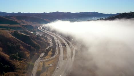 Aerial-Over-Fog-And-Clouds-Along-A-Highway-Through-The-California-Foothills-Near-Ojai-California