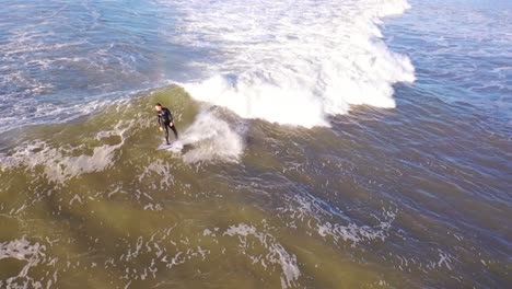 Aerial-Of-Surfer-Surfing-Riding-Large-Ocean-Waves-With-Surf-Breaking-Off-The-Coast-Of-Ventura,-California