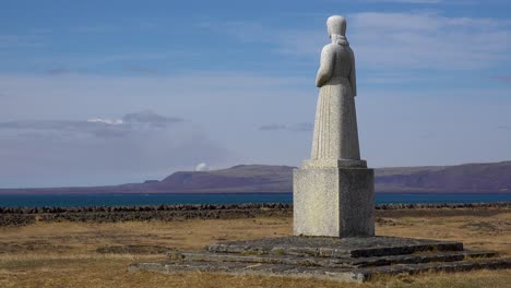 A-Statue-Overlooks-A-Distant-Cloud-Of-Smoke-From-An-Erutping-Volcano,-Iceland