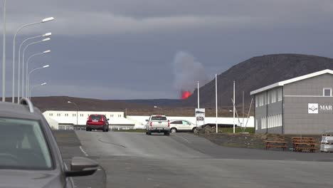 The-Fagradalsfjall-Volcano-Is-Seen-Erupting-In-The-Distance-Behind-The-Town-Of-Grindavik,-Iceland