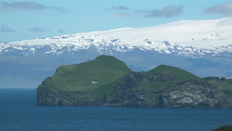 Una-Cabaña-De-Verano-Remota-Y-Solitaria-En-Una-Pequeña-Isla-En-Las-Islas-Westman-De-Islandia-Con-El-Glaciar-Mýrdalsjökull-En-El-Fondo