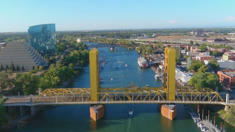 Buena-Toma-Aérea-De-Establecimiento-Del-Río-Sacramento-Y-El-Puente-De-La-Torre-En-Sacramento,-California-Con-Tráfico-De-Botes