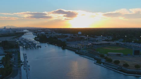 Aerial-Establishing-Shot-Sunset-Of-Sacramento-River,-Stadium-And-Boat-Traffic