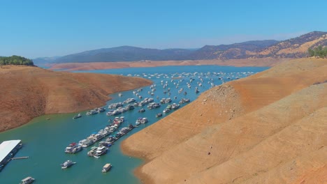 Increíble-Antena-Sobre-El-Lago-Oroville-De-California-Azotado-Por-La-Sequía-Con-Bajos-Niveles-De-Agua,-Costa-En-Retroceso-Y-Casas-Flotantes-Varadas