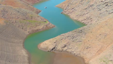 Erstaunliche-Luftaufnahme-über-Dem-Von-Dürre-Betroffenen-Kalifornischen-See-Oroville-Mit-Niedrigem-Wasserstand,-Zurückweichender-Küstenlinie-Und-Verbrannten-Bäumen-Und-Wäldern