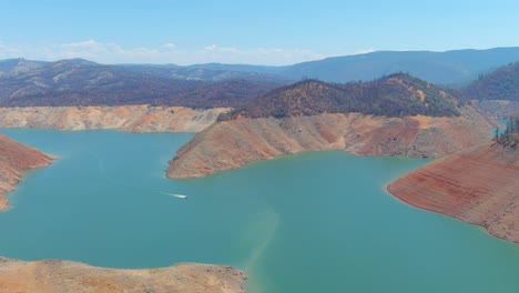 Inquietante-Antena-Sobre-El-Lago-Oroville-De-California-Asolado-Por-La-Sequía-Con-Bajos-Niveles-De-Agua,-Costa-En-Retroceso-Y-Barcos-En-Aguas-Bajas