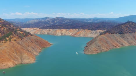 Störende-Luft-über-Dem-Von-Dürre-Betroffenen-Kalifornischen-Oroville-See-Mit-Niedrigem-Wasserstand,-Zurückweichender-Küstenlinie-Und-Booten-Im-Niedrigwasser