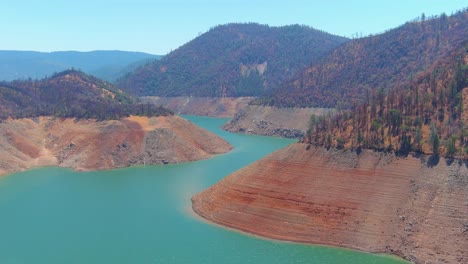 Störende-Luft-über-Dem-Von-Dürre-Betroffenen-Kalifornischen-Oroville-See-Mit-Niedrigem-Wasserstand,-Zurückweichender-Küstenlinie-Und-Booten-Im-Niedrigwasser