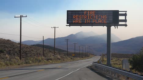 Ein-Elektronisches-Schild-Entlang-Einer-Autobahn-Warnt,-Dass-Feuerbeschränkungen-Gelten,-Während-Das-Caldor-feuer-Im-Hintergrund-In-Der-Nähe-Von-Lake-Tahoe,-Kalifornien,-Wütet