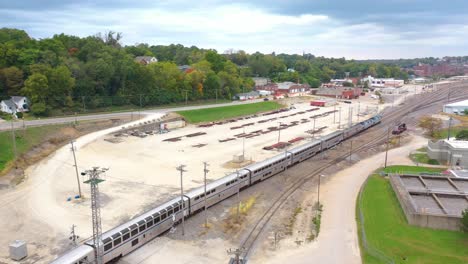 Antenne-Eines-Langstrecken-Amtrak-Personenzuges-Kommt-In-Einem-Rangierbahnhof-In-Der-Nähe-Von-Burlington,-Iowa-An