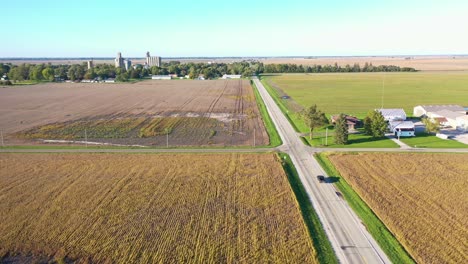 Aerial-Over-Pickup-Truck-Traveling-On-A-Straight-Highway-Leading-Into-A-Small-Town-In-Rural-Iowa,-Indiana-Or-Illinois