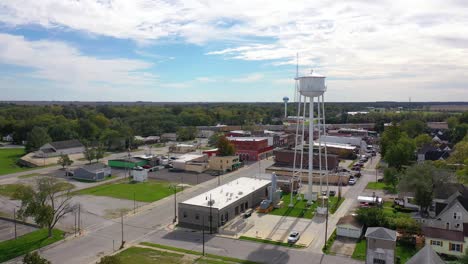 Luftaufnahmen-über-Hauptstraße-Kleinstadt-USA-Mit-Wasserturm-Und-Güterzug-Vorbei-Am-Hintergrund