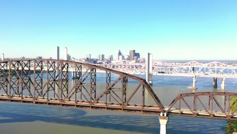 Antena-Sobre-Los-Puentes-Del-Río-Ohio-Con-El-Horizonte-Del-Centro-De-Louisville,-Kentucky-Distante