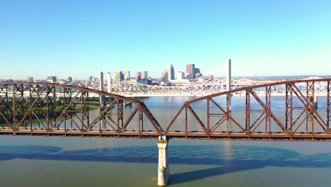 Antena-Sobre-Los-Puentes-Del-Río-Ohio-Con-El-Horizonte-Del-Centro-De-Louisville,-Kentucky-Distante