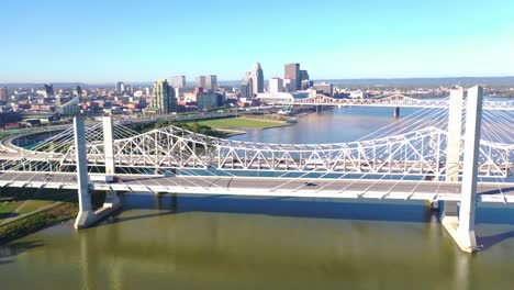 Antena-Sobre-Los-Puentes-Del-Río-Ohio-Con-El-Horizonte-Del-Centro-De-Louisville,-Kentucky-Distante