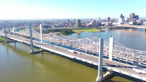 Aerial-Over-Ohio-River-Bridges-With-The-Louisville,-Kentucky-Downtown-Skyline-Distant-Suggests-Infrastructure