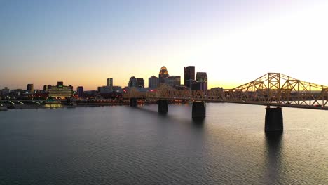 Buen-Anochecer-Toma-Aérea-De-Establecimiento-De-Louisville,-Horizonte-Del-Centro-De-Kentucky,-Con-El-Puente-Conmemorativo-George-Rogers-Clark-En-Primer-Plano