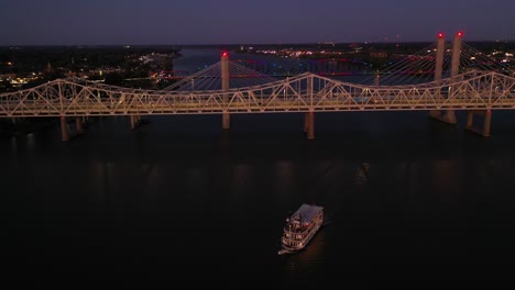 Antena-Nocturna-De-Puentes-Y-Botes-De-Paletas-En-El-Río-Ohio-En-Jeffersonville,-Indiana-Y-Louisville,-Kentucky