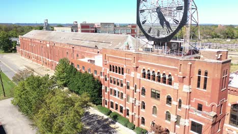 Rising-Aerial-Of-A-Large-Old-Clock-On-The-Facade-Of-An-Old-Abandoned-Vacant-American-Factory-Near-Jeffersonville,-Indiana