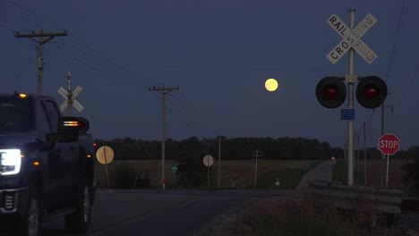 Ein-Kleintransporter-überquert-Nachts-Bei-Vollmond-In-Der-Ferne-Einen-Bahnübergang