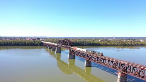 Antena-De-Un-Tren-De-Carga-Que-Cruza-El-Río-Ohio-En-Un-Puente-Ferroviario-De-Acero-Cerca-De-Louisville,-Kentucky