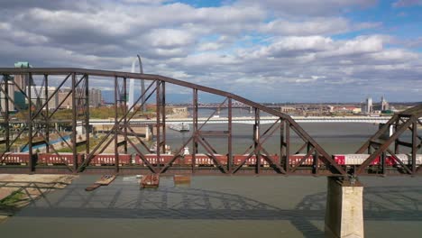 Antenne-Eines-Güterzugs,-Der-Den-Mississippi-River-Mit-Dem-St.-Louis-Gateway-Arch-Und-Dem-Hintergrund-Der-Skyline-Der-Stadt-überquert