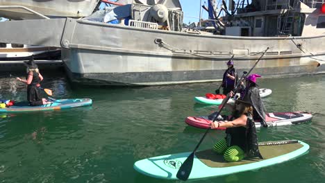 Witches-In-Costume-Paddle-On-Surfboards-And-Paddleboards-To-Celebrate-Halloween-In-Ventura-Harbor,-California