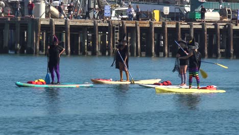 Witches-In-Costume-Paddle-On-Surfboards-And-Paddleboards-To-Celebrate-Halloween-In-Ventura-Harbor,-California