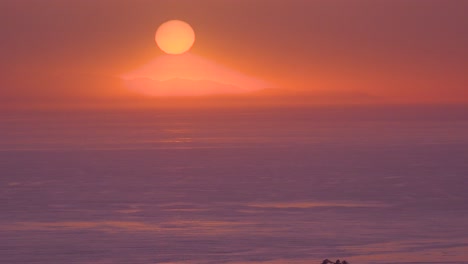 Una-Enorme-Bola-Redonda-Roja-De-Sol-Al-Atardecer-Sobre-El-Océano-Pacífico-Cerca-De-Malibu,-California