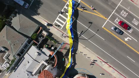 Manifestantes-Ucranianos-Aéreos-De-Arriba-Hacia-Abajo-Con-Una-Gran-Bandera-Ucraniana-Protestan-Por-La-Invasión-Rusa-De-Su-País,-En-La-Calle-En-Malibu,-California-Con-El-Cartel-De-Malibu