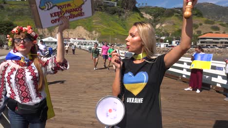 Top-Down-Aerial-Ukrainian-Protesters-With-Large-Ukraine-Flag-Protest-The-Russian-Invasion-Of-Their-Country,-On-Pacific-Coast-Highway-In-Malibu,-California-With-Malibu-Sign