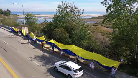 Ukrainische-Antikriegs-Demonstranten-Aus-Der-Luft-Zeigen-Eine-Lange-Flagge-Und-Schilder-Auf-Dem-Pacific-Coast-Highway-PCH-Malibu,-Kalifornien,-Um-Gegen-Die-Russische-Invasion-In-Der-Ukraine-Zu-Protestieren