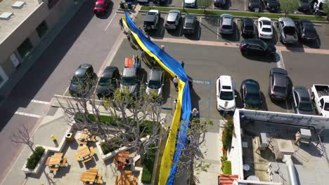 Aerial-Ukrainian-Antiwar-Protesters-Display-A-Long-Flag-In-A-Generic-Parking-Lot-To-Protest-The-Russian-Invasion-Of-Ukraine