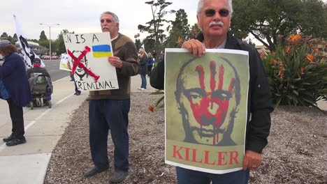 Protesters-Gather-To-Hold-Signs-In-Support-Of-Ukraine-Following-Russia-Invasion,-With-One-Sign-Identifying-Putin-As-A-Killer