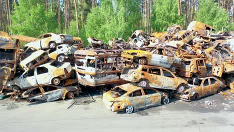 Antena-Ascendente-De-Autos-Destrozados-Y-Quemados-En-El-Cementerio-De-Autos-Sentados-En-Una-Pila,-Muchos-Con-Agujeros-De-Bala-De-La-Agresión-Rusa,-Irpin-Ucrania