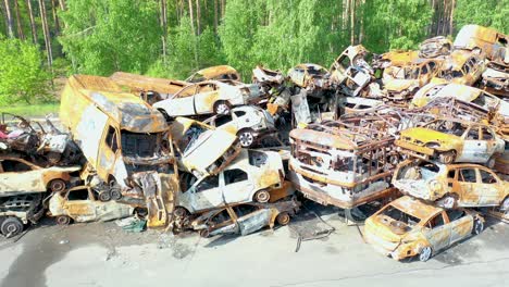 Rising-Aerial-Of-Wrecked-And-Burned-Cars-In-The-Car-Cemetery-Sitting-In-A-Pile-Many-With-Bullet-Holes-From-Russian-Aggression,-Irpin-Ukraine