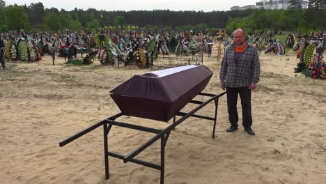 A-Man-Stands-Beside-The-Coffin-Of-A-Dead-Relative-In-A-Cemetery-In-Irpin,-Ukraine,-A-Suburb-Of-Kyiv