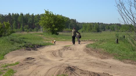 Ein-Alter-Mann-Geht-Mit-Seinem-Hund-Und-Seinem-Fahrrad-In-Der-Ländlichen-Ukraine-Auf-Einem-Feld-Spazieren