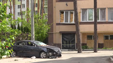 A-Car-With-Multiple-Bullet-Holes-Sits-In-A-Parking-Lot-Of-A-Destroyed-Ukrainian-Apartment-Complex-In-Irpin,-Ukraine,-During-War