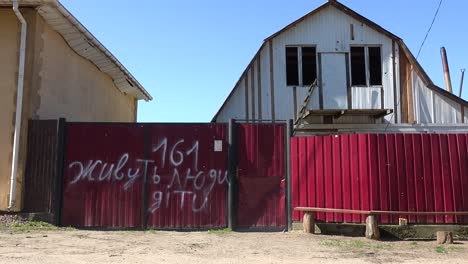 Una-Casa-Destrozada-En-Moschun-Tiene-Un-Letrero-En-La-Puerta-En-Ruso-Que-Dice-Que-La-Gente-Vive-Allí,-Durante-La-Guerra-De-Ucrania