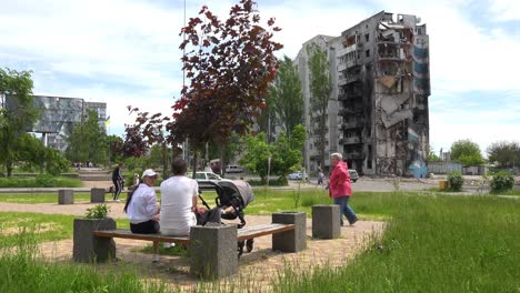 La-Gente-Camina-Por-Un-Parque-Devastado-En-Borodianka,-Borodyanka,-Ucrania-Con-Edificios-De-Apartamentos-Bombardeados-Y-Disparados-Con-Cohetes-Donde-Cientos-Fueron-Asesinados-Por-La-Ocupación-Rusa