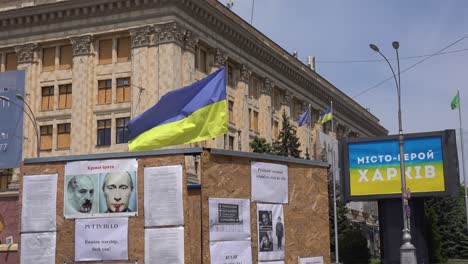 Eine-Schwarze-Tafel-Auf-Dem-Zentralen-Platz-Von-Charkiw-Zeigt-Putin-Und-Lukaschenko-Als-Blutrünstige-Mörder-Und-Blutsbrüder-Und-Eine-Plakatwand-In-Der-Nähe-Kündigt-An,-Dass-Charkiw-Eine-Heldenstadt-Der-Ukraine-Ist