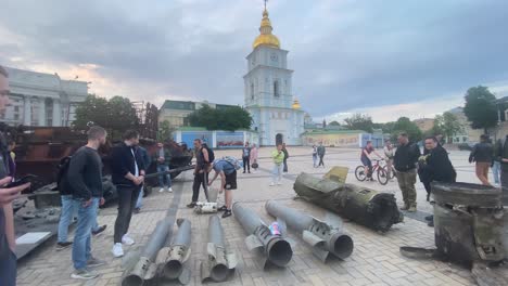 Ukrainians-Admire-Russian-Bombs-And-Other-War-Wreckage-Sitting-In-A-Square-In-Downtown-Kyiv,-Kiev-Ukraine