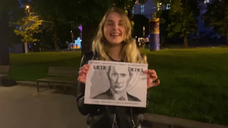 Young-Girl-Shows-Off-Bullet-Holes-In-Putin'S-Face-After-Shooting-His-Image-With-An-Air-Rifle-On-The-Street-In-Central-Lviv,-Ukraine