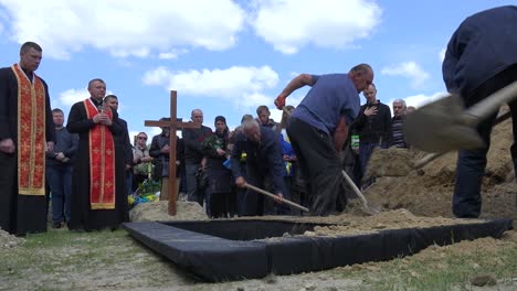 Arbeiter-Schaufeln-Frische-Erde-In-Ein-Offenes-Grab-Auf-Einem-Friedhof-In-Lemberg,-Ukraine,-Während-Einer-Soldatenbeerdigung